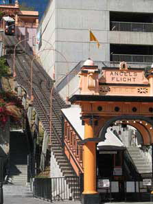 Excerpt From Angels Flight
(Photo Credit: Hal Bastian)
Bosch had ridden the incline railroad as a kid and had studied how it worked. He still remembered. The two matching cars were counterbalanced. When one went up the side by side tracks the other went down, and vice versa. They passed each other at the midpoint. He remembered riding on Angels Flight long before Bunker Hill had been reborn as a slick business center of glass and marble towers, classy condominiums and apartments, museums and fountains referred to as water gardens. Back then the hill had been a place of once grand Victorian homes turned into tired looking rooming houses. Harry and his mother had taken Angels Flight up the hill to look for a place to live. Angels Flight Railway