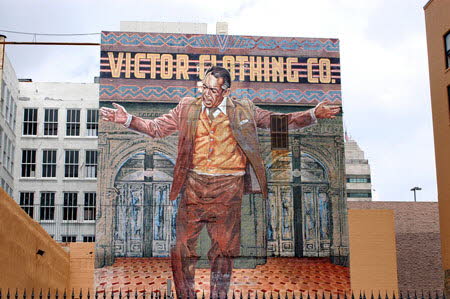 Excerpt From Angels Flight (Photo by Wendy Werris)
In the last room he noticed that through the windows behind Elias's large polished wood desk he could see the huge face of Anthony Quinn. It was part of a mural depicting the actor with arms outstretched on the brick wall of a building across the street from the Bradbury.
Rider came into the office behind him. She looked out the window, too.
"You know every time I'm down here and see that I wonder who that is."
"You don't know?"
"Cesar Chavez?"
"Anthony Quinn. You know, the actor."
He got a nonresponse from her.
"Before your time, I guess. The mural is called the Pope of Broadway, like he's watching over all the homeless around here."
"Oh, I see." She didn't sound impressed. "How you want to do this?"
Bosch was still staring at the mural. He liked it, even though he had a hard time seeing Anthony Quinn as a Christ-like figure. But the mural seemed to capture something about the man, a raw masculine and emotional power. Bosch stepped closer to the window and looked down. He saw the forms of two homeless people sleeping under blankets of newspapers in the parking lot beneath the mural. Anthony Quinn's arms were outstretched over them. Bosch nodded. The mural was one of the little things that made him like downtown so much. Just like the Bradbury and Angels Flight. Little pieces of grace were everywhere if you looked. Anthony Quinn Mural