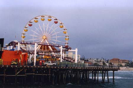 Excerpt From Chasing The Dime (Photo by Wendy Werris)
The neon lights on the Ferris wheel on the Santa Monica pier were on and flashing a repetitive pattern. It made him remember a time two years earlier when the company had rented the pier's entire amusement park for a private party celebrating the approval of the company's first batch of patents on molecular memory architecture. No tickets, no lines, no getting off a ride if you were having fun. He and Nicole had stayed in one of the open yellow gondolas of the Ferris wheel for at least a half hour. It had been cold that night too and they huddled against each other. They'd watched the sun go down. Now he couldn't look at the pier or even a sunset without thinking about her.
In acknowledging this about himself he realized he had rented an apartment with views of the very things that would remind him of Nicole. There was a subliminal pathology there that he didn't want to explore at the moment. Santa Monica Pier & Ferris Wheel