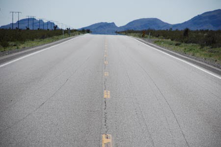 Excerpt From The Scarecrow (Photo by Terrill Lee Lankford)
Highway 93 took me past Nellis Air Force Base and then connected with 50 North. It wasn't too long before I began to see why it was known as the loneliest road in America. The empty desert ruled the horizon in every direction. Hard, chiseled mountain ranges, barren of any vegetation, rose and fell away as I drove. The only signs of civilization were the two-lane blacktop and the power lines carried over the ranges by iron stick figures that looked like they were giants from another planet. The Loneliest Road in America